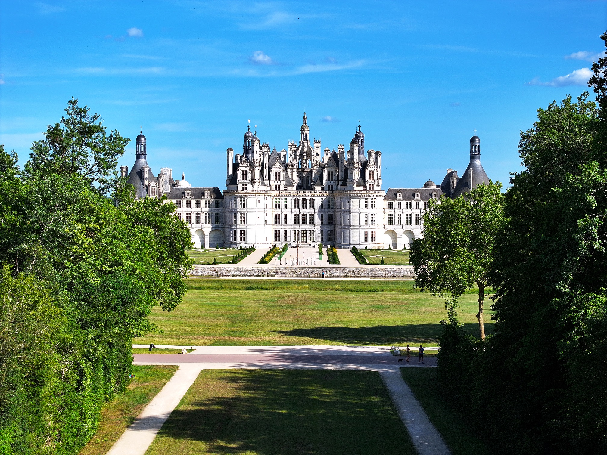 Majestic Château de Chambord mirrored in the calm waters on a clear day.